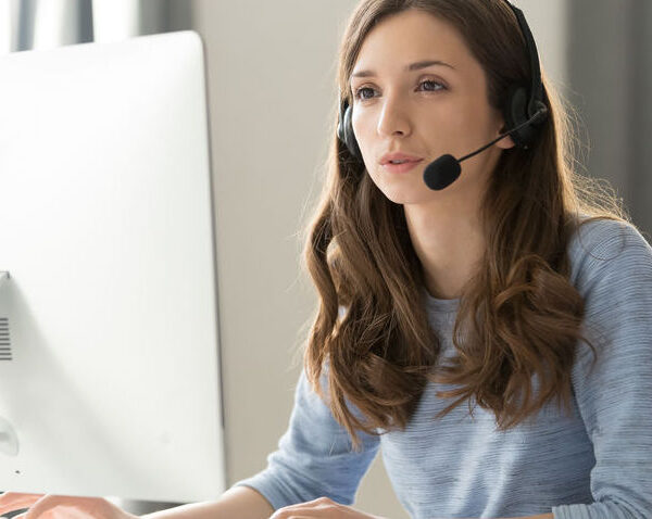 Serious young businesswoman in wireless headset call center agent telemarketer consulting client participating business video conference talk help as customer care service support helpline in office.