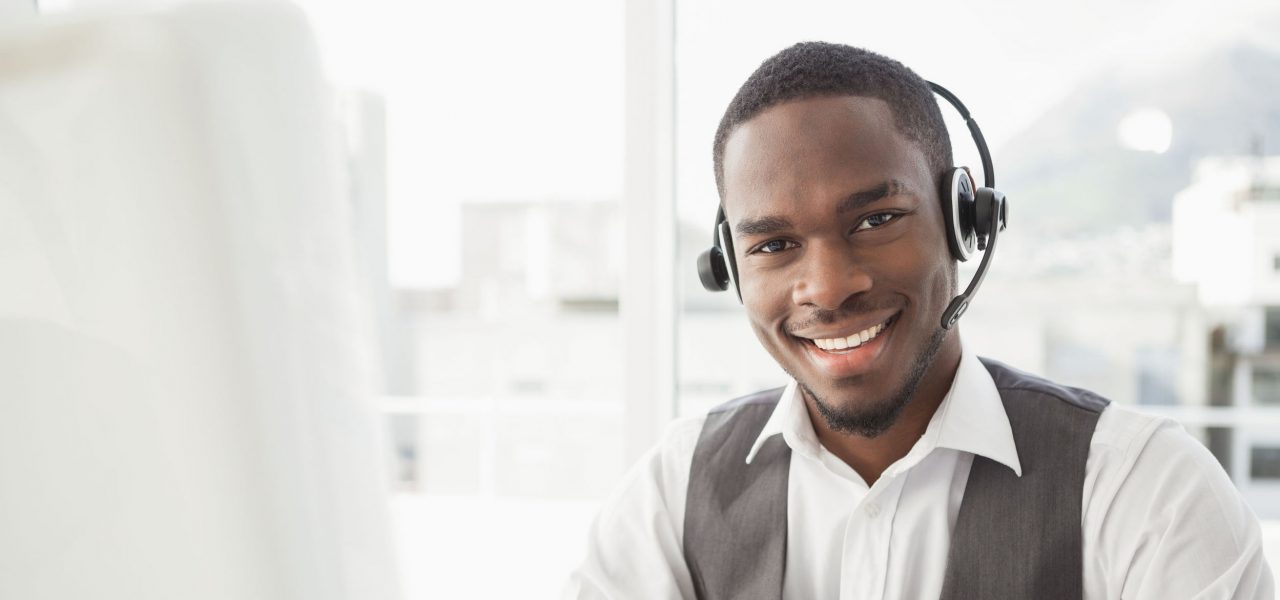 Happy businessman with headset interacting in his office